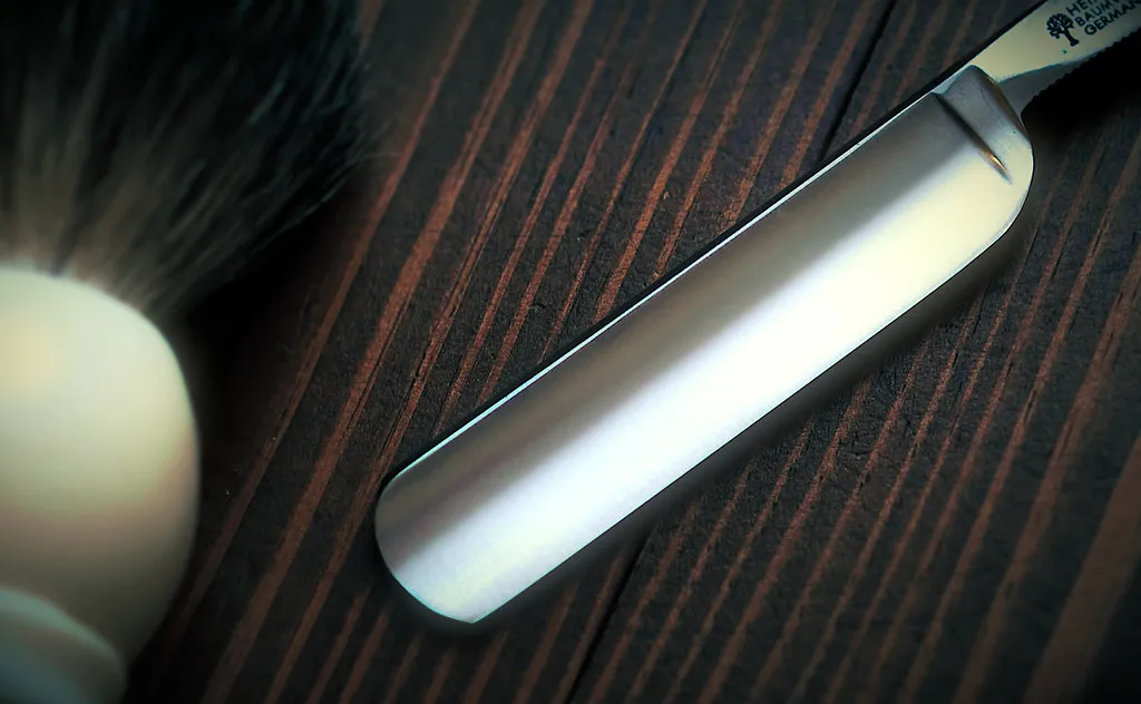 A straight razor and shaving brush on a barber's bench